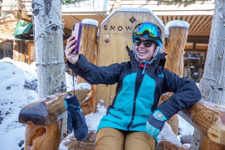 person with ski gear on sits in chair and takes a selfie with phone during eventzee scavenger hunt app event at snowmass