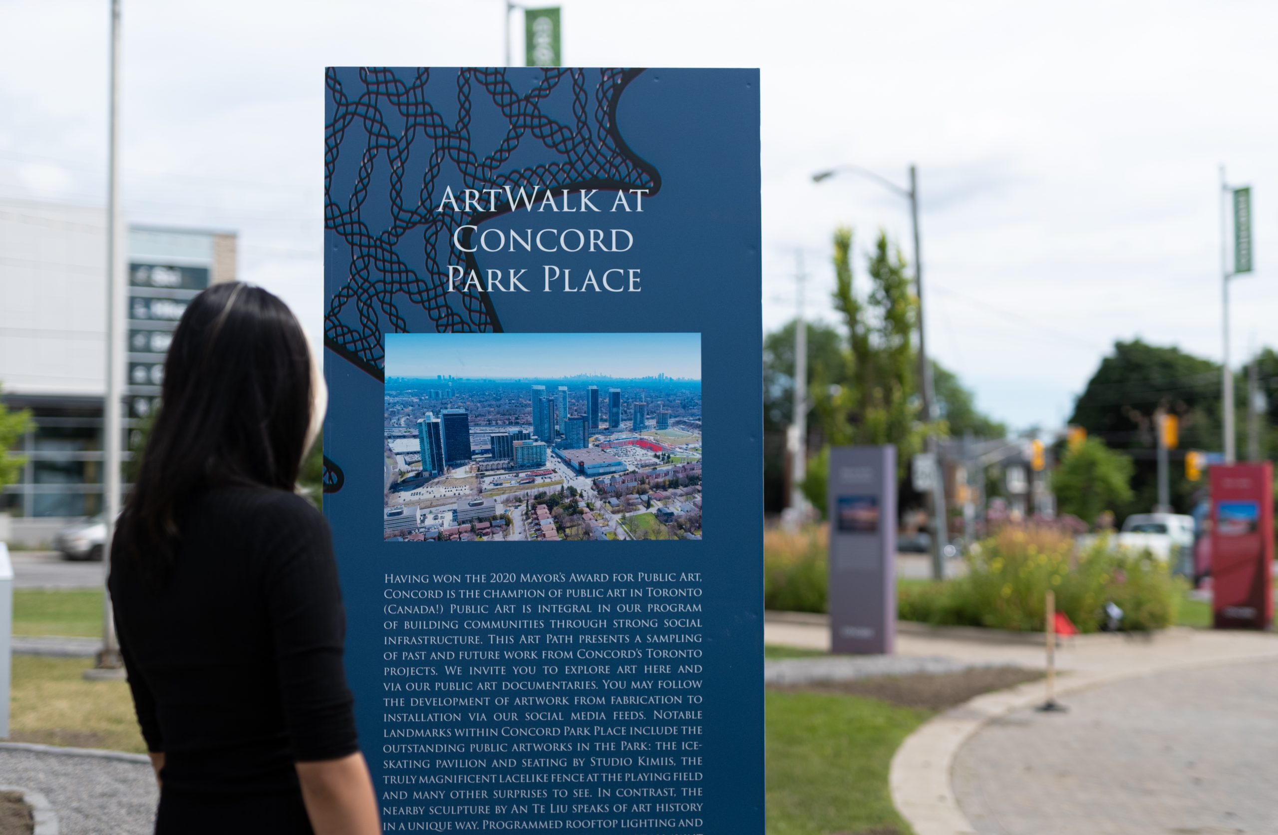 image featuring woman looking at small information board about artwalk at concord park place with event using eventzee scavenger hunt app